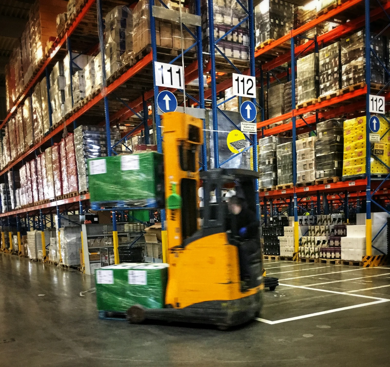 Forklift operating between warehouse storage racks